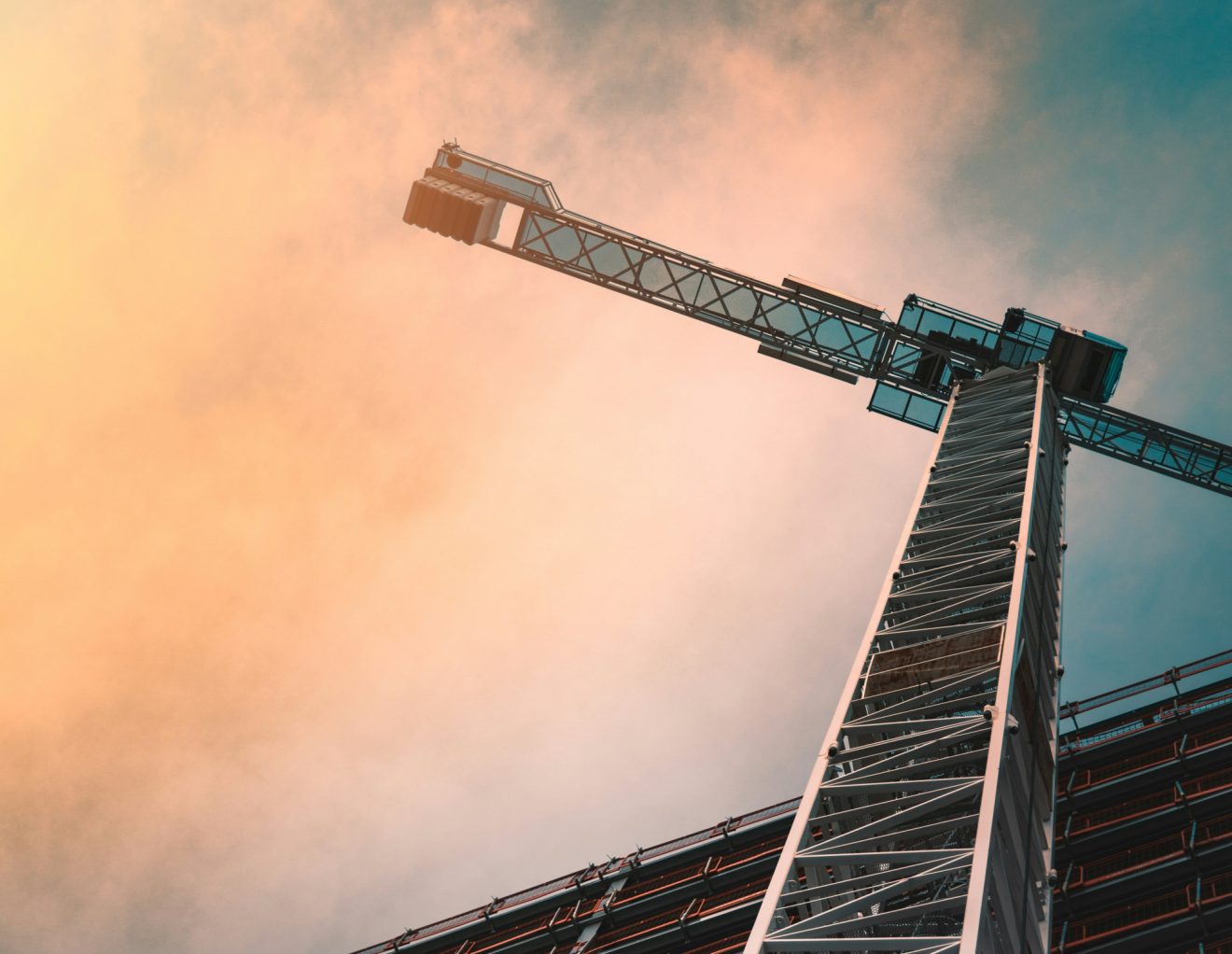 An image of a construction crane against a sunset sky