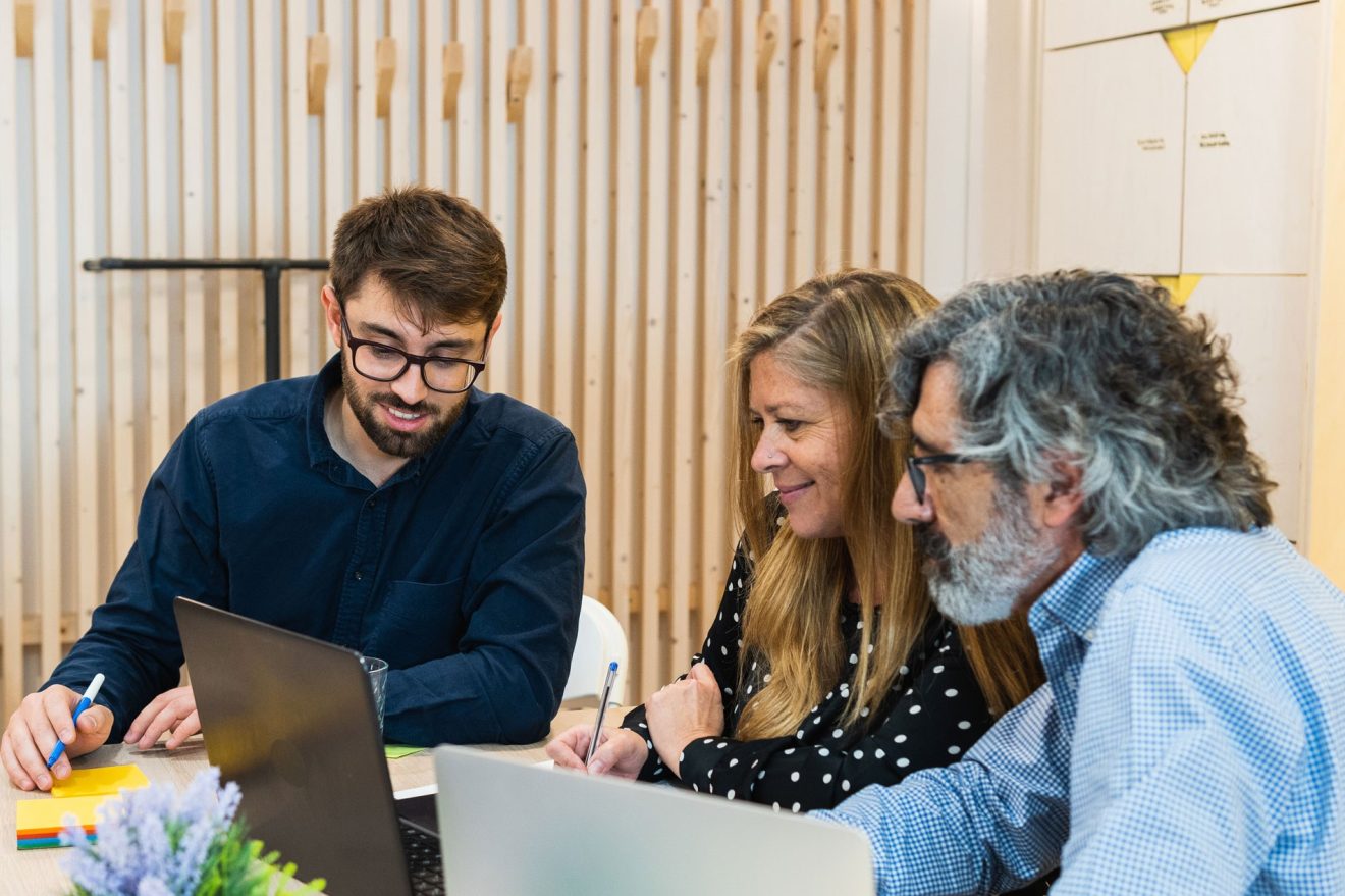 Three people at a table with open laptops