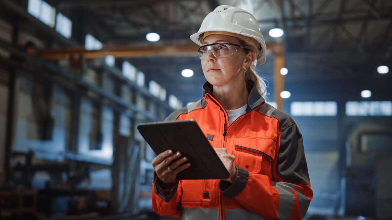 Woman wearing a hard hat holding tablet in a warehouse