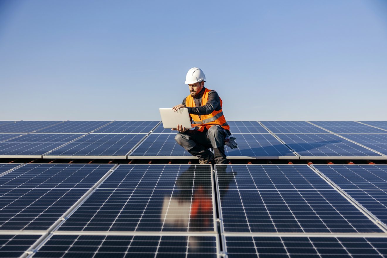 A man looks at Quickbase on a laptop in a solar field