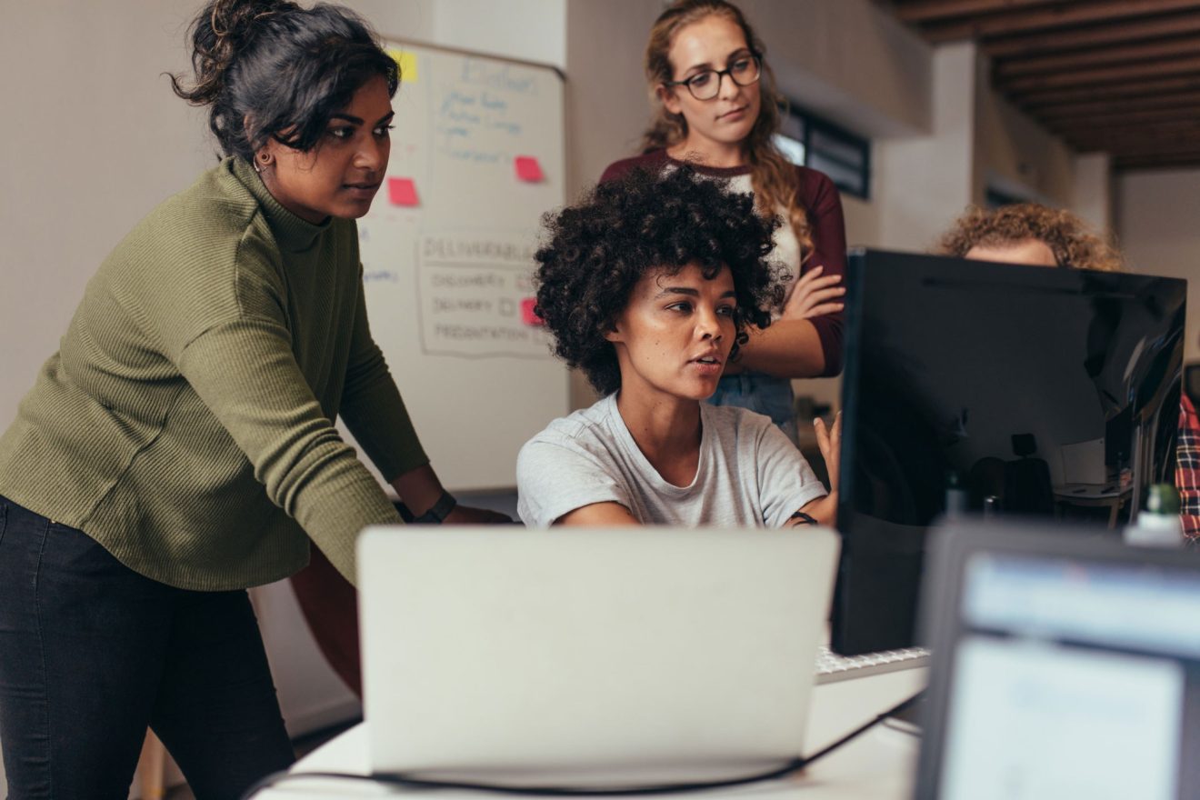 Four people work together on a computer
