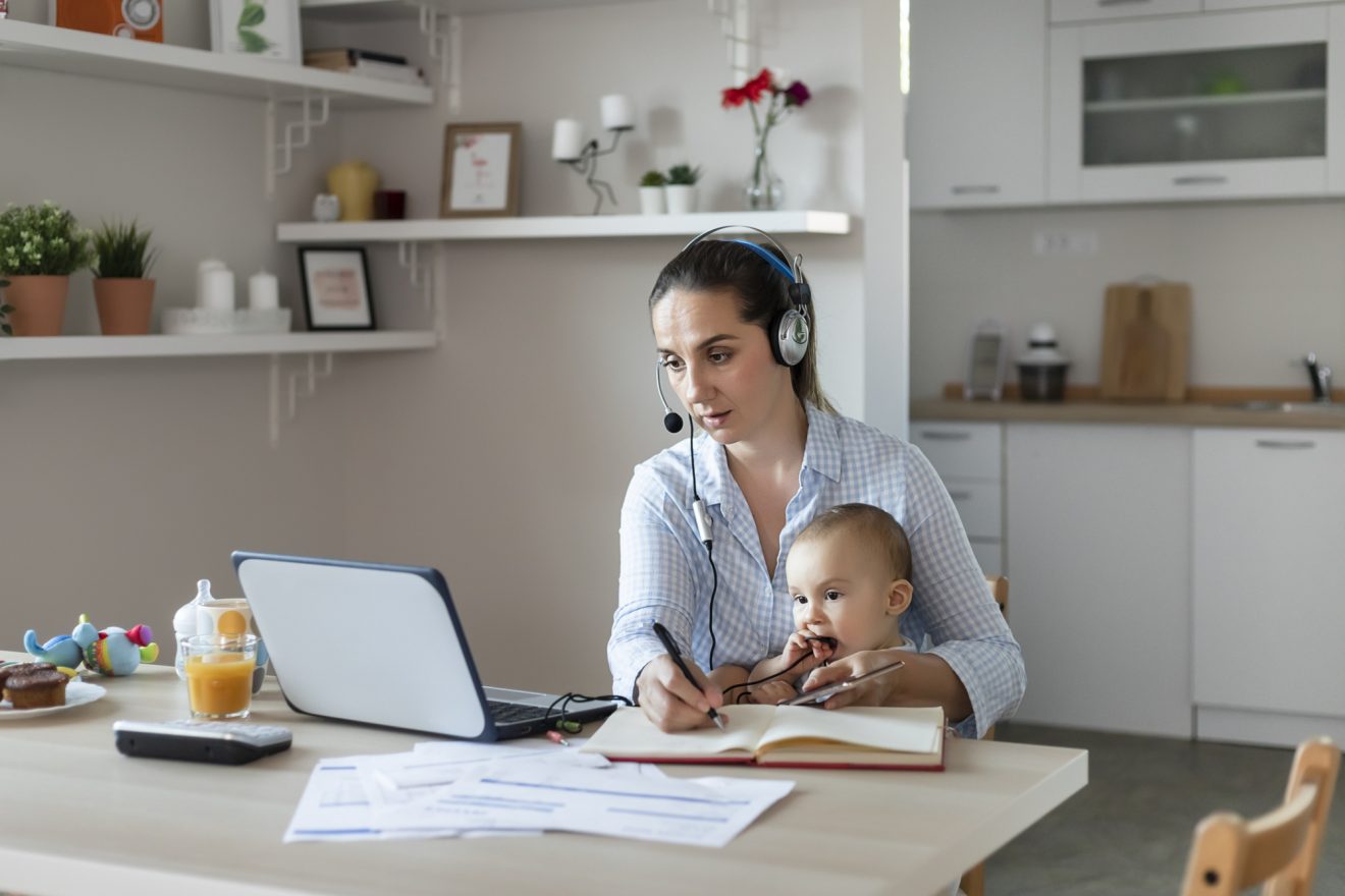 A woman attends a training from home with her baby on her lap