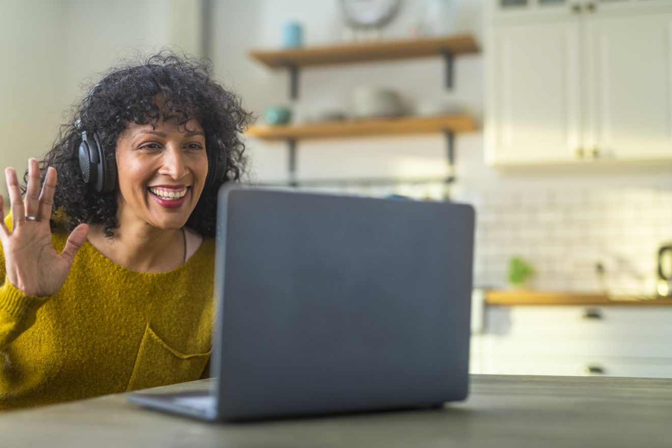 A woman greets her coworkers on a video call